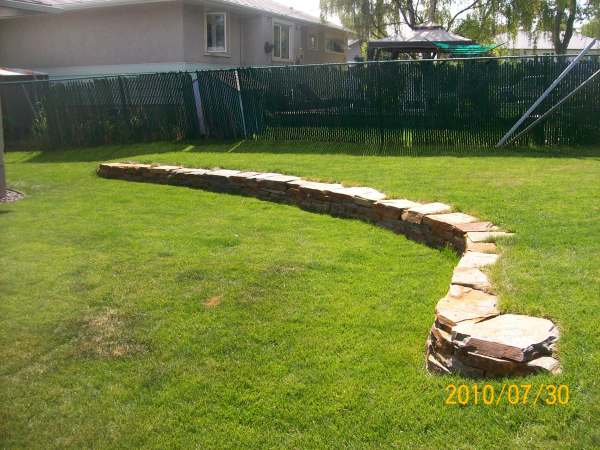 ... sloped backyard. Adding garden beds in and around the wall will soften