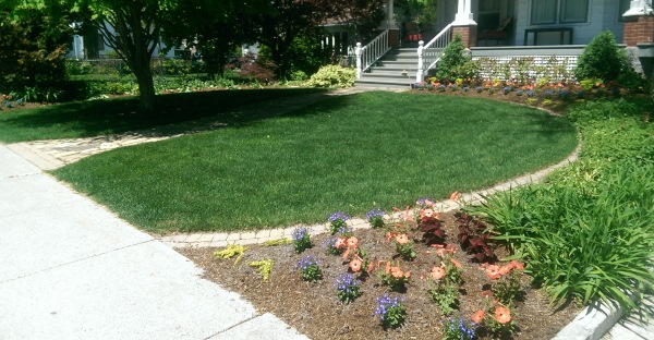 A simple way to define up a front yard circular garden bed with a border of mow over bricks.