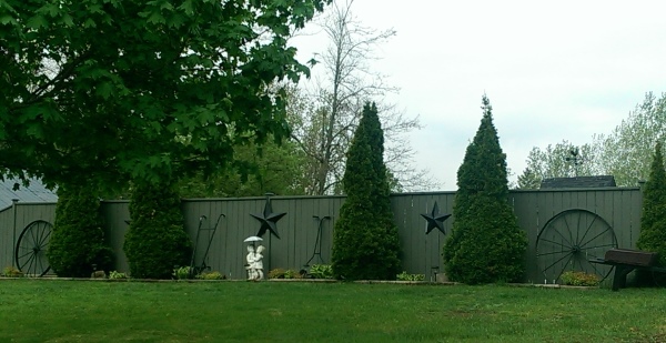 This side yard fence is creatively dressed up with old tools between the evergreens that provide form all year round.