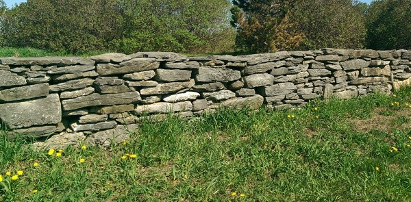 A dry stacked fieldstone wall at the entrance to a large acreage property. Fieldstone provides the weathered look like the wall has been there for centuries.