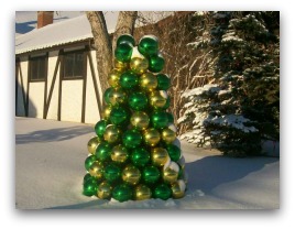 A small tree made out of ornamental Christmas balls stands prominent in this snowy winter scene.