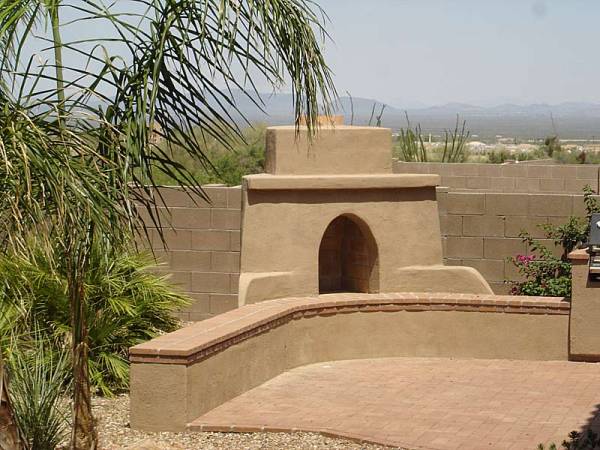 A small patio area for a BBQ and outdoor fireplace well designed to incorporate the distant mountains in the scene while taking the eye off the block privacy wall.