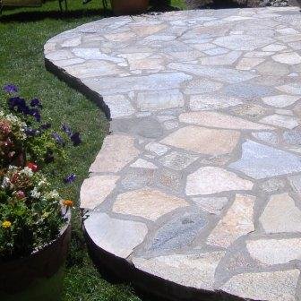 A raised flagstone patio spills out over a lush green lawn. 