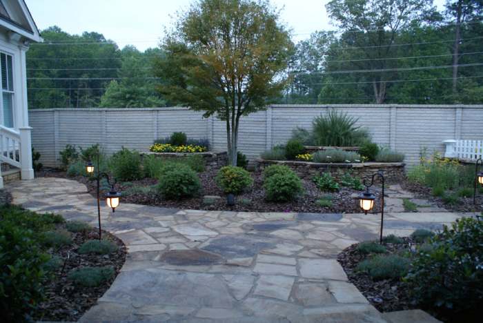 Wide natural stone walkway splitting into two smaller walkways that stroll through perennial planted mulch beds.