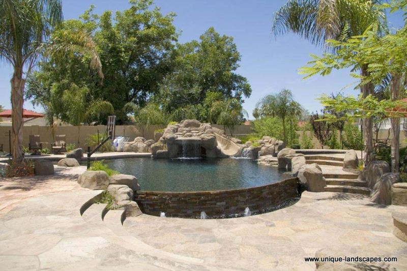 A beautiful flagstone patio with stairs molded into boulder features around this stunning pool.