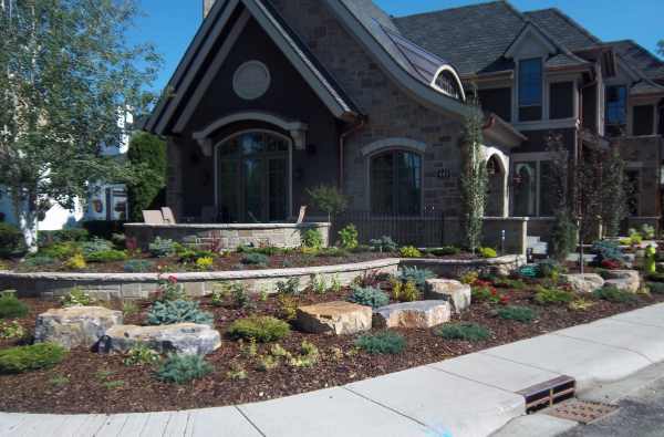 Beautiful corner lot landscaping with formal stone walls are interplanted with a shrub and mulch rock garden.