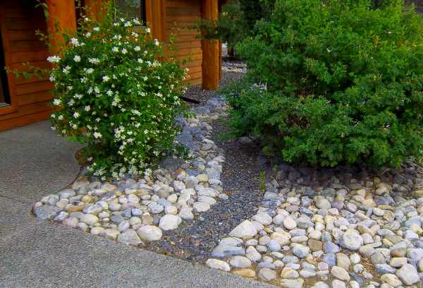 Front yard river rock landscaping ideas are easy ways to eliminate maintenance. Adding a small gravel river bed is simple way to dress up this simple design.