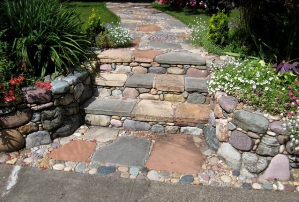 Mixed stone steps with small garden beds on either side lead to up to a beautiful mosaic stone walkway.