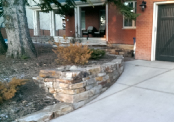 A mixed colour dry stacked stone wall makes a great addition to the front of this home.