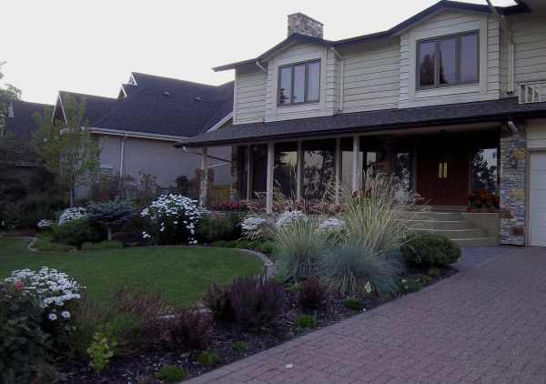 A mixed ornamental grass and perennial garden wrap this front lawn for some great color and front yard curb appeal.