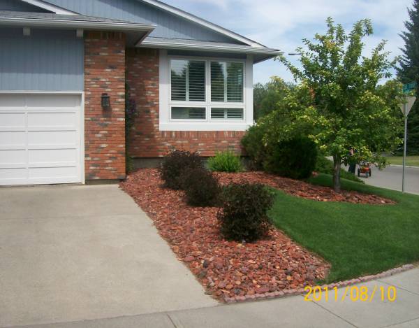 Driveway landscaping on a corner lot with a decorative rock to match the brickwork.