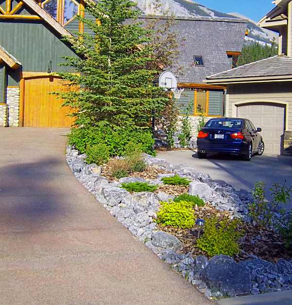 Driveway landscaping between two neighbors with a small slope can be challenging. Instead of building a small retaining wall and separating the properties, try simple rock garden ideas like this.