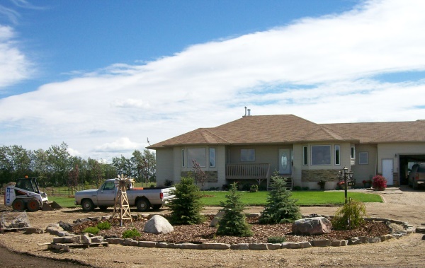 A simple, easy and affordable front yard circular driveway idea in a country setting. Large border stones placed around a perimeter of mulch over landscape fabric.