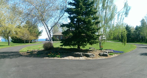 A long circular driveway with a low maintenance center island rock garden welcomes visitors to this lakeside home.