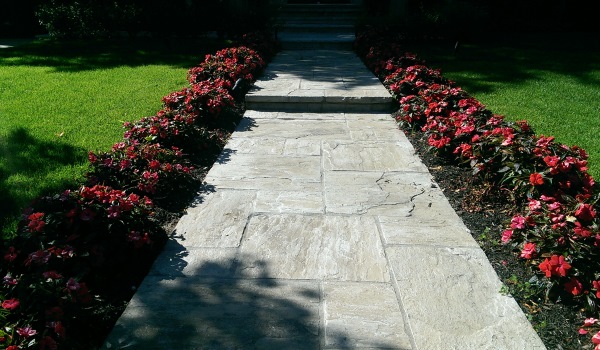 A cut flagstone walkway is a formal way to dress up a front entrance. Spaced plantings provide repetition and a nice rhythm to the walkway.