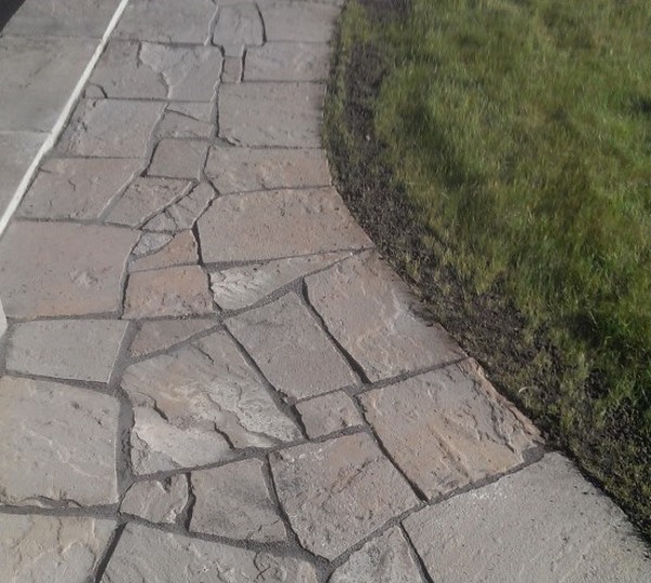 A dry laid flagstone walkway with 1-2 inch gaps wraps around the back of an acreage home. The joints have been filled with polymeric jointing sand.