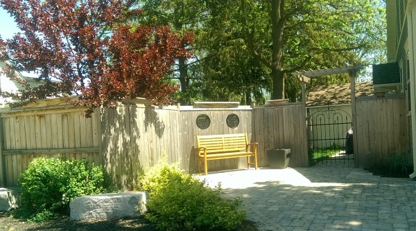 This simple wooden fence has so much character with the top rail trim, windows and the gate arbour.