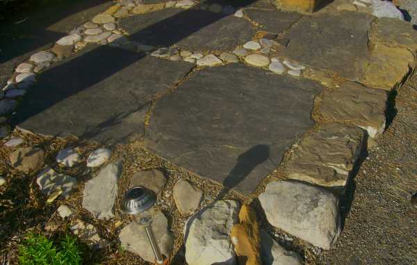 A small seating area in this backyard has a simple base of flagstone with river rock.
