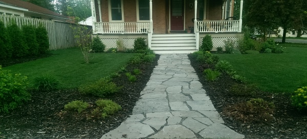 A simple flagstone walkway lined with mulch and perennials creates some interest in this front yard.