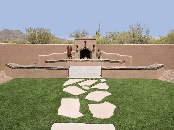 A natural flagstone walkway set in the lawn leads to an outdoor fireplace area. 