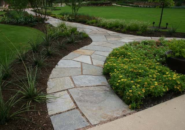 Formal cut stone split arched walkway that wraps around a nice perennial bed.