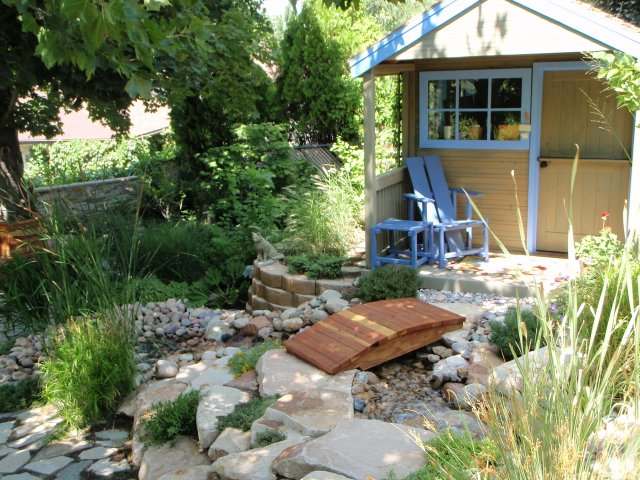 Ornamental grasses and a few shrubs give life to the stones used in this water feature.