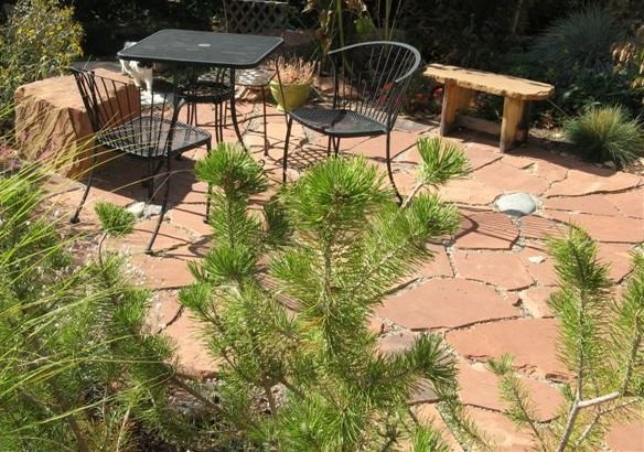 An informal rustic style flagstone patio with some fieldstones randomly placed in the large gaps.