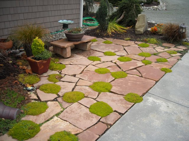 A miniature stone bench for a planter, planting between the patio stones, and other items give this small patio area character and charm.