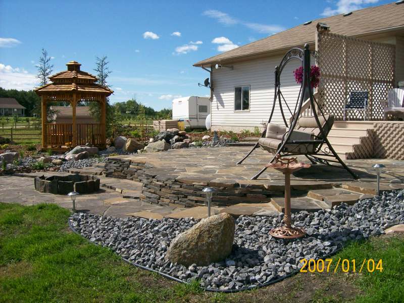 A multi-level patio was built with stairs wrapping around both sides to blend in the patio to the existing slope in this yard.