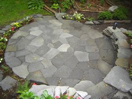 A great overhead shot of a flagstone patio showing the back wall and front garden bed.