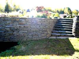 This flagstone wall curves nicely into a set of natural stone steps.
