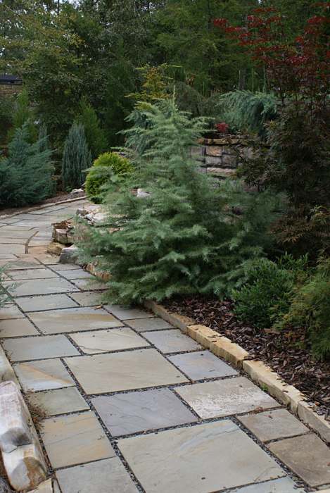 Cut flagstone walkway with a low border of natural stone blocks. 