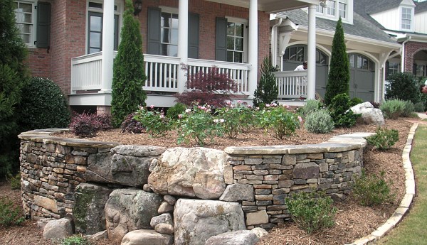 This beautiful front yard retaining wall of mixed stones makes a nice level area for a perennial bed.