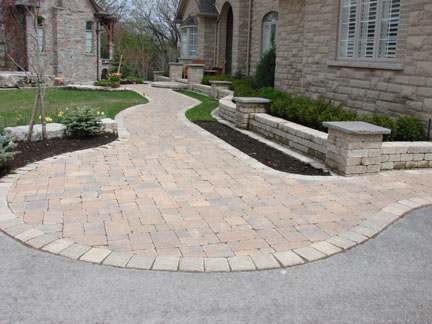 A wide opening tastefully blended into the driveway leads to the front entry of a large house.