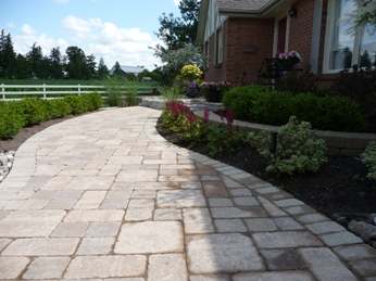 A formal brick walkway leads to the front of this house. It has nice subtle curves to border the beds on each side of it. Notice the repetition