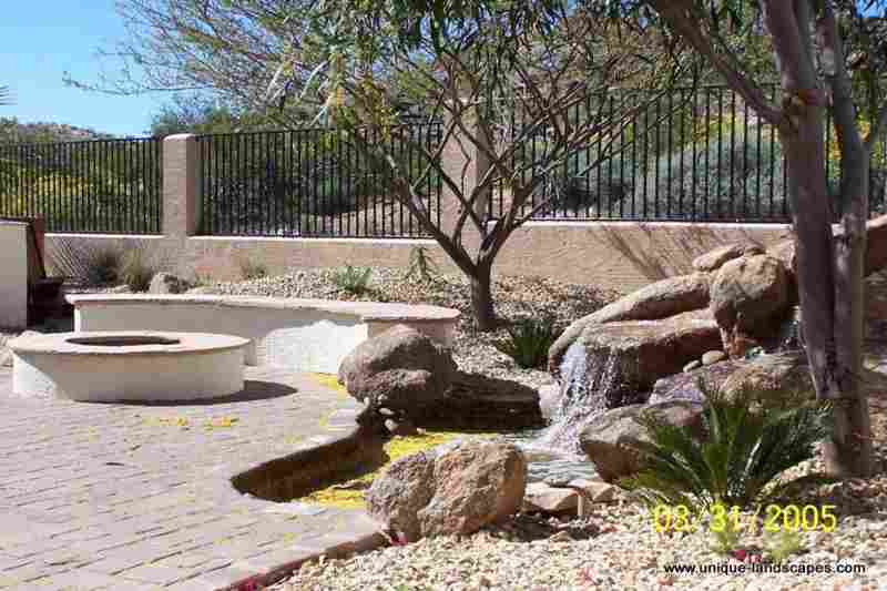 A nice brick patio area with a firepit and seating surrounded by natural desert plants.