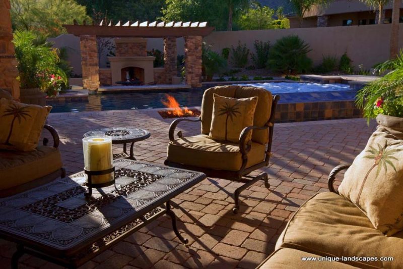 Beautiful patio brickwork, tile, and natural stone pillars surround this backyard pool.