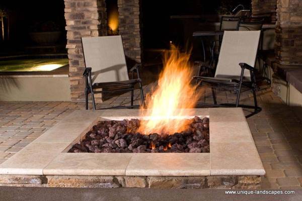 This firepit is set just off an outdoor kitchen and a hot tub.