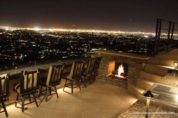 Watching over the city lights on a formal deck, with the warmth of an outdoor fireplace at your side.
