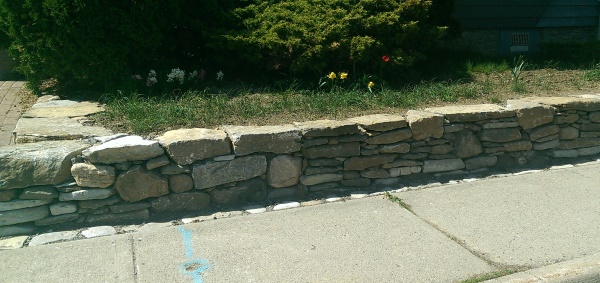 A mixed fieldstone wall gives this small town home a quant look with some curb appeal.