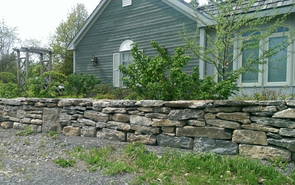 A mixed fieldstone wall provides a nice barrier to this front of this country property.