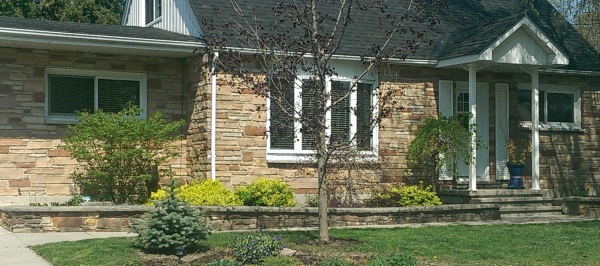 A low mortared fieldstone wall compliments the stone wall facing on this home. The wall is topped off with manufactured capping stone.