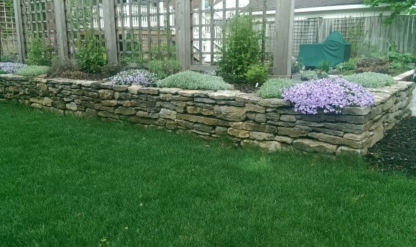 Outdoor rooms can be separated in many ways. In this case two outdoor rooms are separated using a stone wall and raised planter bed combined with lattice for more privacy.