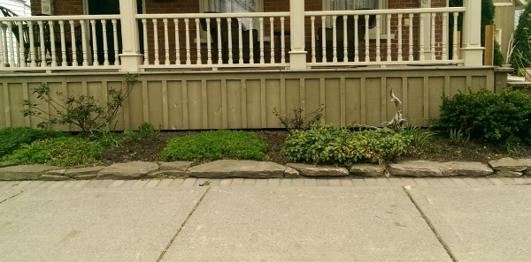 Even a small front yard can still have a little curb appeal along the sidewalk. A simple one tiered stone wall dresses up a front porch on this older home.