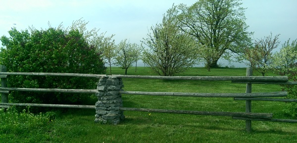 A Wooden fence with natural stone built pillars looks right at home for this large lakeside property.
