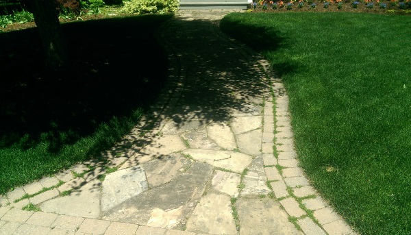 A weathered flagstone front walkway has a creative double brick soldier course to define the edges.