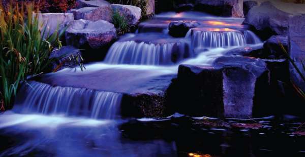 A nicely designed multi-cascade water feature is lined with just the right stones and plants.